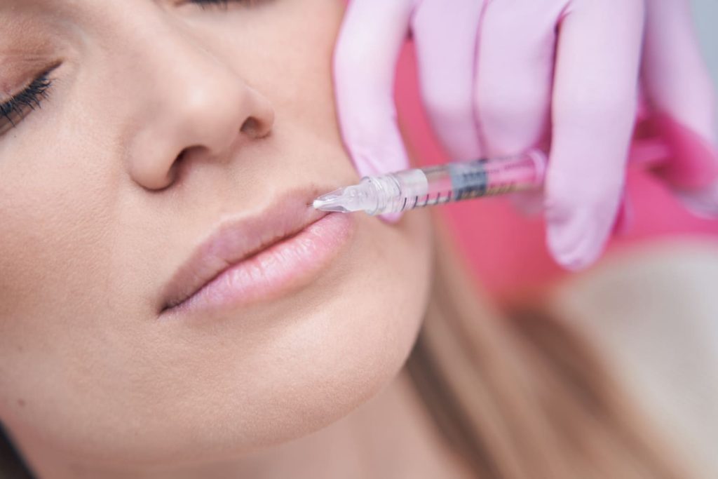 Profesional de la salud aplicando una inyección en los labios de una paciente.