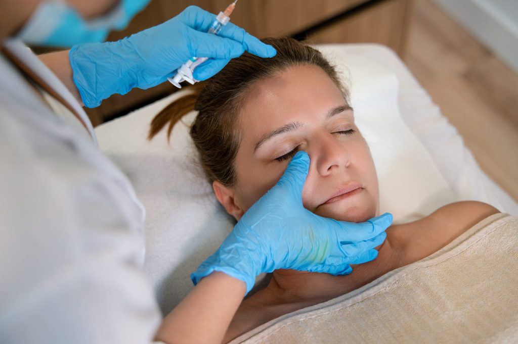 Profesional de la estética aplicando inyección en la frente de una paciente relajada.